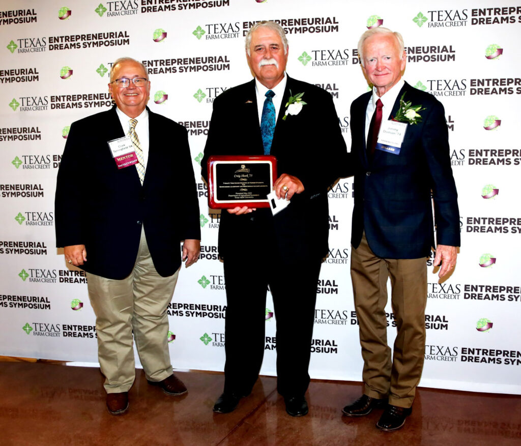 Craig Shook standing in middle holding plaque with Clark Springfield, Ph.D., left, and Jimmy Dodson '74, right, receiving the Tyrus Timm honor.