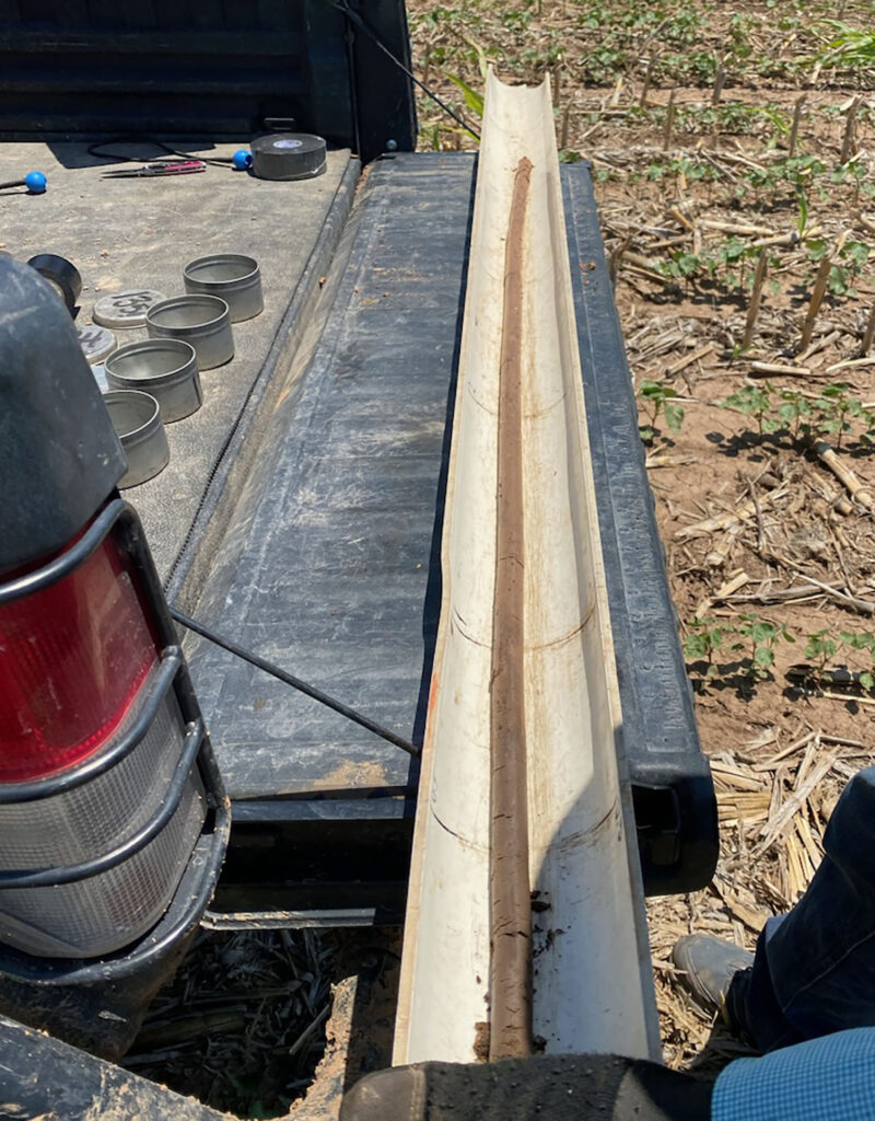 a long soil core sits on the back of a pickup truck tailgate