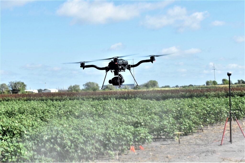 A drone with a camera attached to it flies over crops in a field