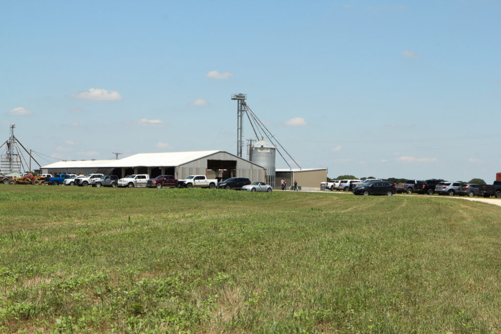 Foto del corral de engorde del Centro de Investigación McGregor de Texas A&M con varios camiones y autos estacionados cerca