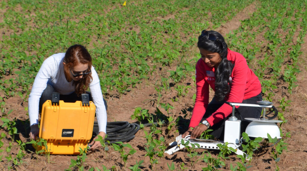 Dos mujeres en un campo revisando la calidad del suelo.