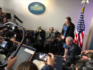 Leslee Oden y un hombre sentado están detrás de un pavo.  Todos están rodeados de fotógrafos y reporteros durante una conferencia de prensa en la Casa Blanca.