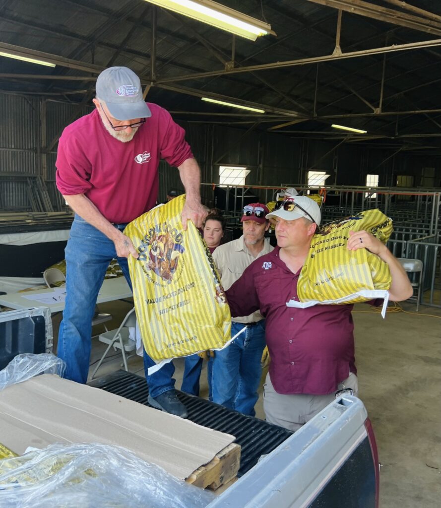 Three men and a woman who are Disaster Assessment and Recovery agents unload feed from a pickup truck. DAR is expanding its statewide disaster preparedness, response and recovery efforts
