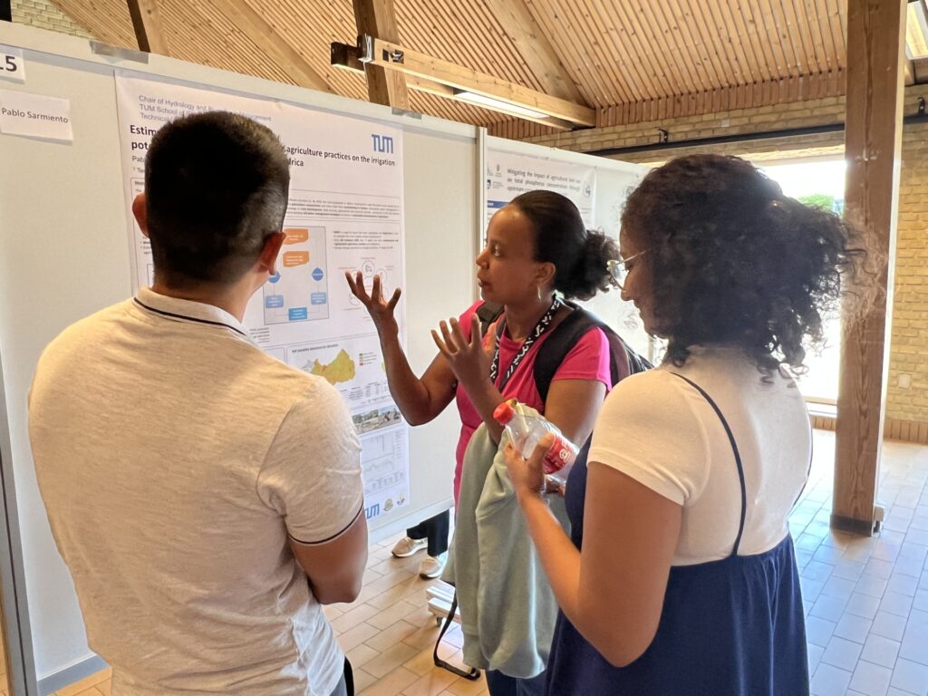 Three people in casual attire gathered around and discussing a scientific poster at the SWAT conference. SWAT is a predictive computer melding system.