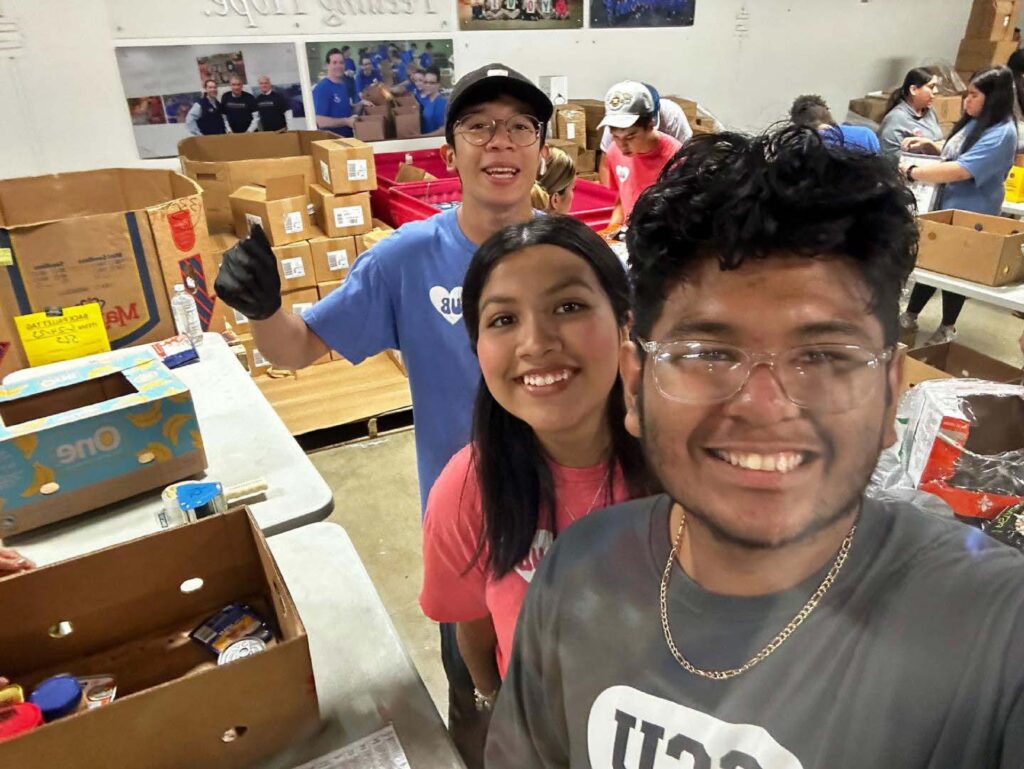 Photo of two men and a woman who are volunteering with the Trinity Upward Bound program at the San Antonio Food Bank
