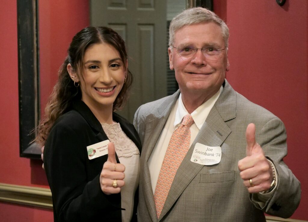 A woman, left, and a man standing together giving a thumbs up to the camera 