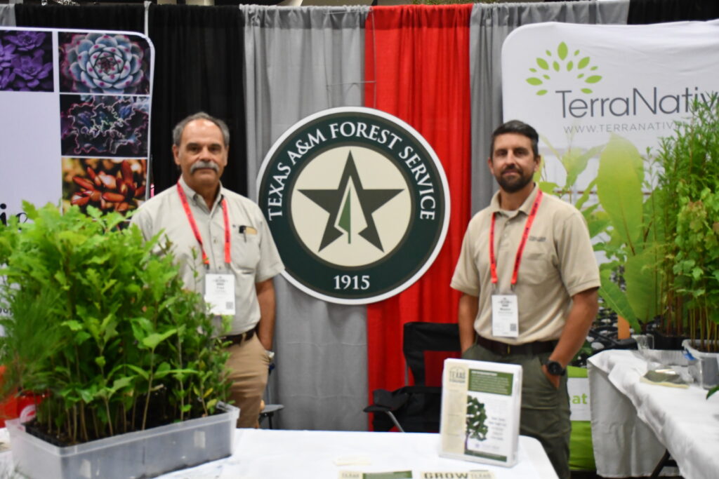 Two men from the Texas A&M Forest Service stand at the agency's booth at the TNLA expo