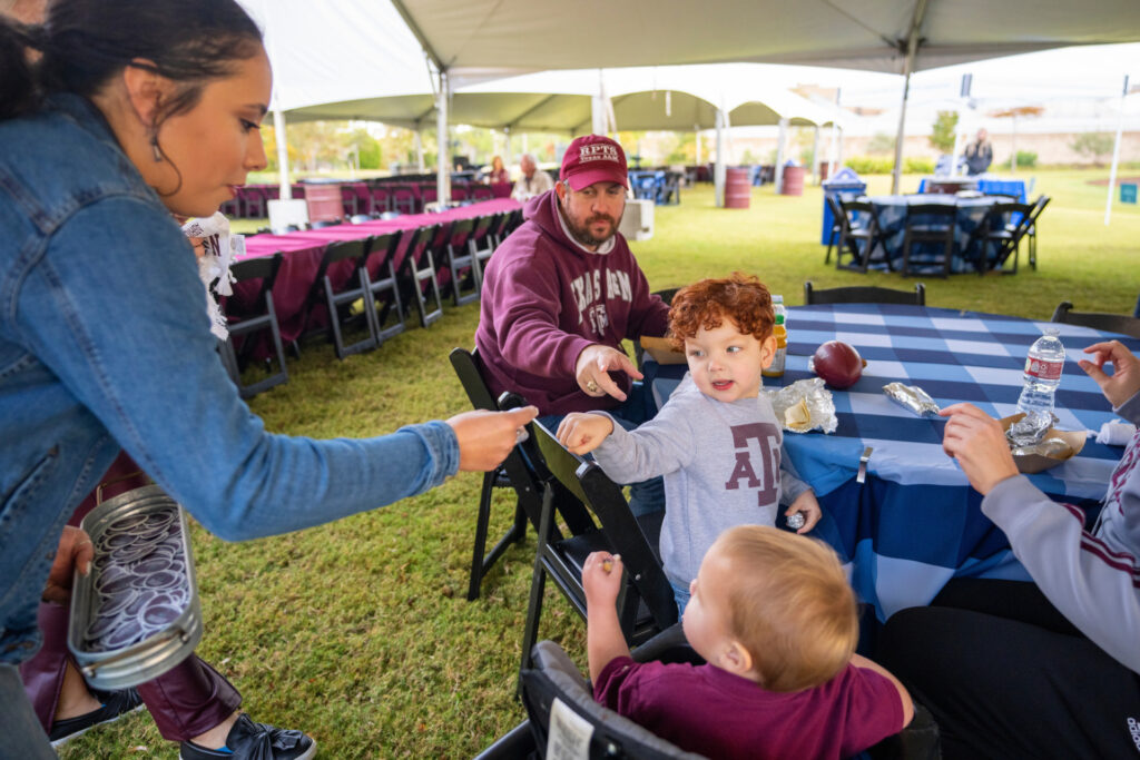 A picnic table with an Aggie family sitting around it before a game.