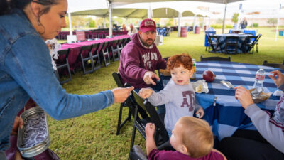 A picnic table with an Aggie family sitting around it before a game.