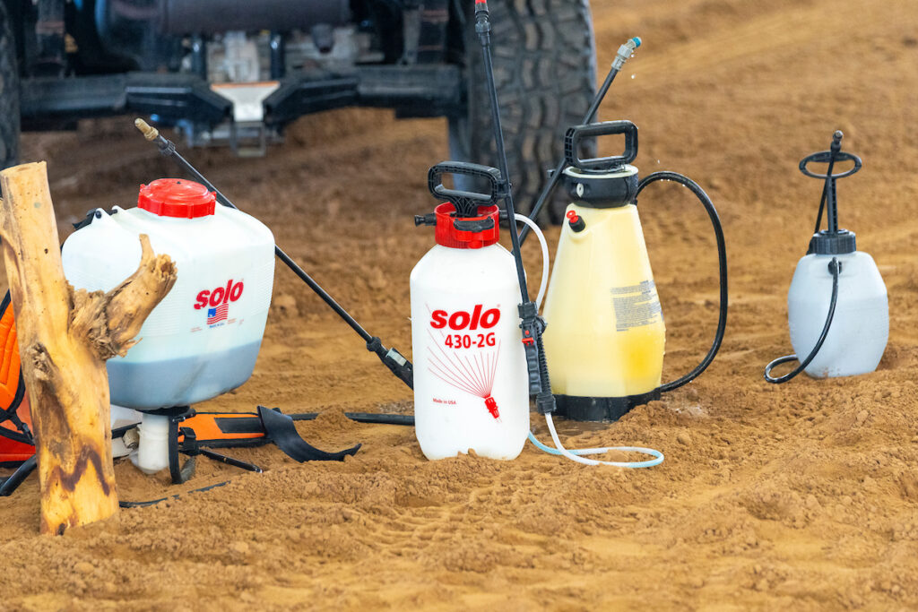 pesticide sprayer bottles sit on the ground ready for application. 