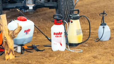 Sprayer bottles sit on the ground ready for application.
