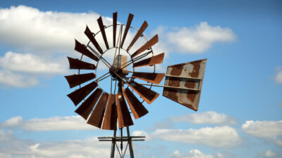 Rusty windmill with clouds in the background.