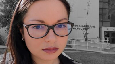 A headshot of doctoral cadidate Karla Solis Salazar. She has long dark hair and wears dark framed glasses and a red lip.