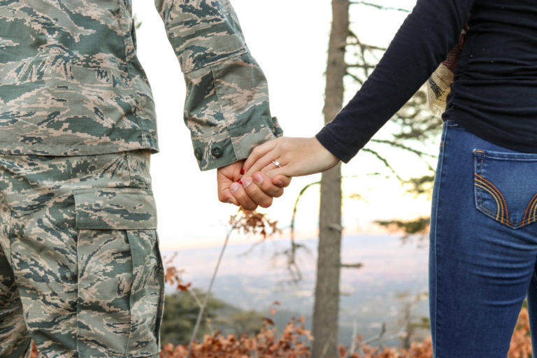 A man on the left is wearing military fatigues and the woman on the right are holding hands. The Sept. 27 webinar will focus on importance of maintaining self-care and mental health while serving others.