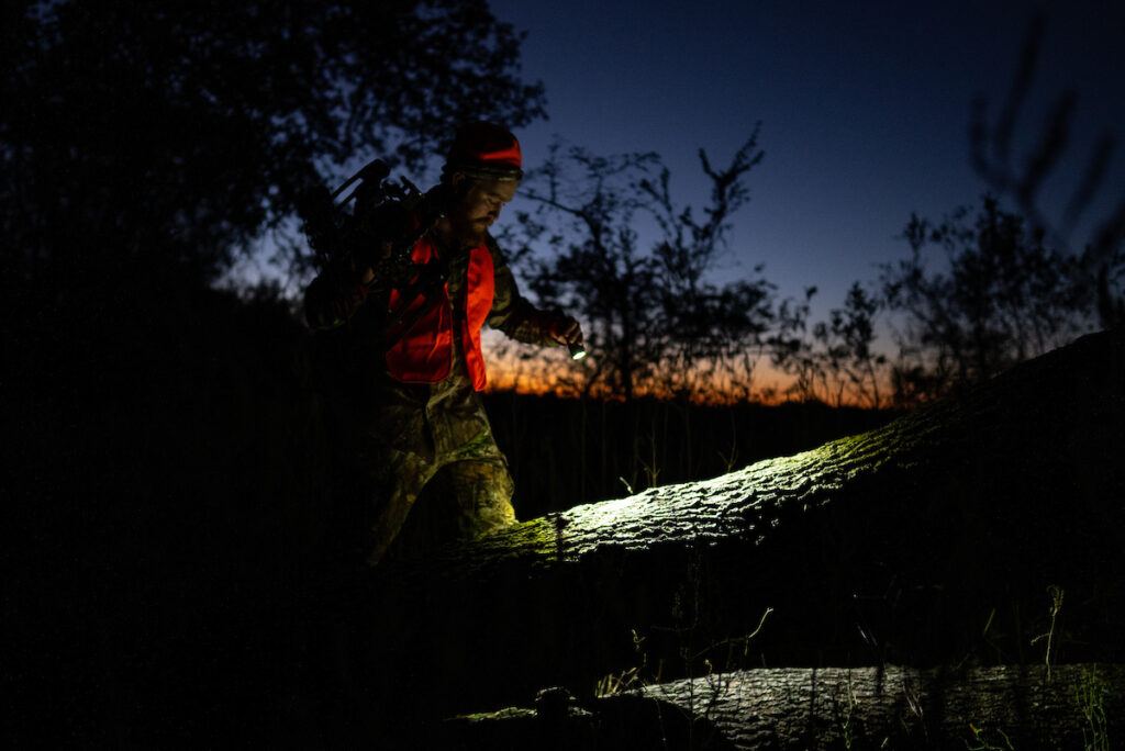 A hunter walks through the dark with a flashlight to his hunting spot. 