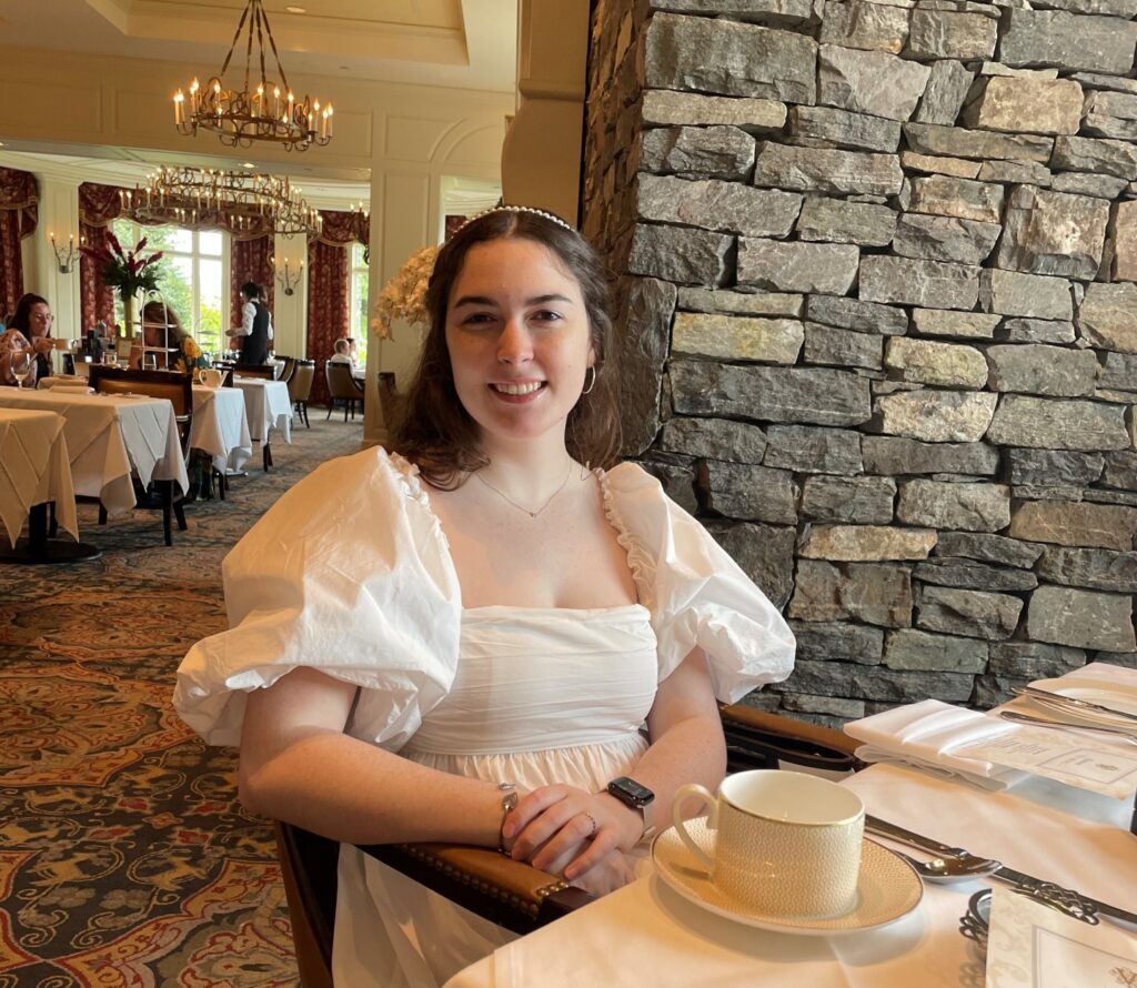 A woman, Mackenzie Mathews, sitting in a dining rom wearing an elegant white dress