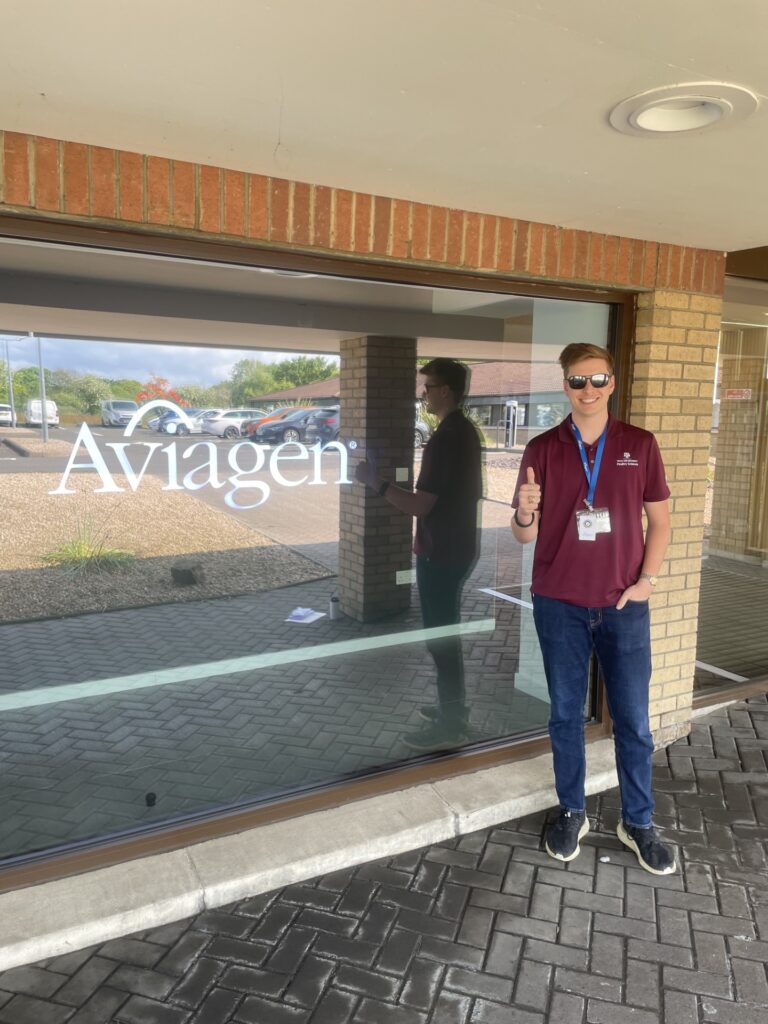 Kolton Witherspoon standing in front of a window with text on it that reads "Aviagen".