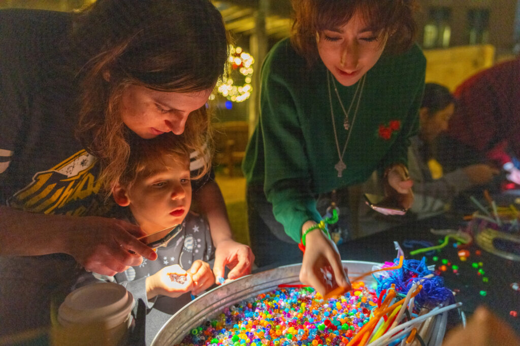 Two female adults and a male child work on a craft project at the Holiday Stroll in The Gardens at Texas A&M University.