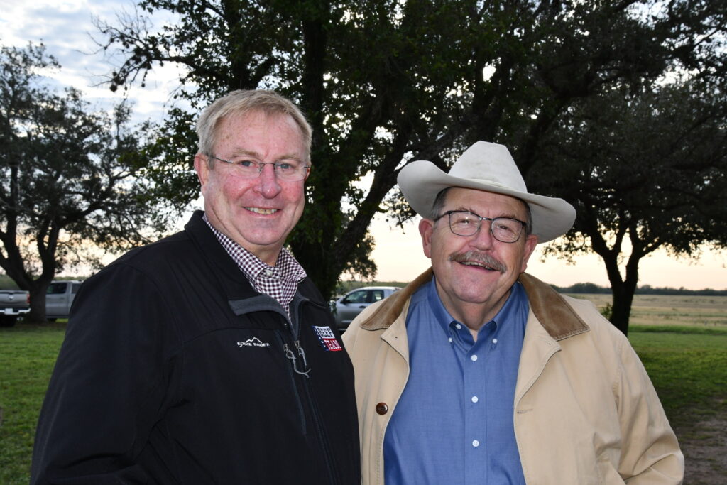 Two gentlemen, G. Cliff Lamb and Joe Paschal, in front a tree at the Beeville station field days. Lamb is wearing a black jacket with a checkered shirt underneath and Paschal is wearing a tan jacket with a blue short and a cowboy hat