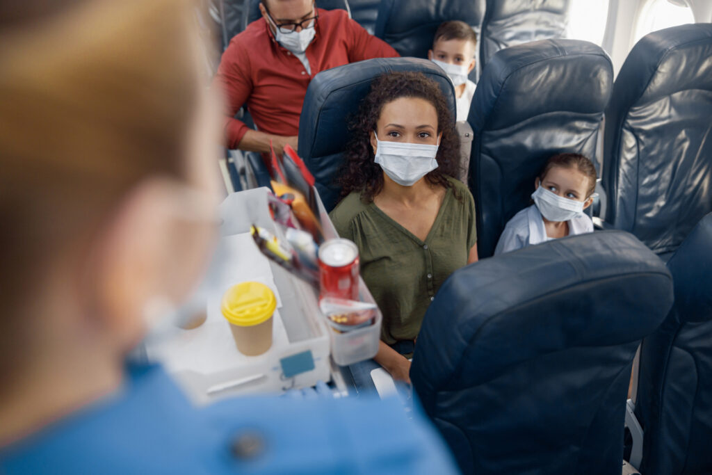 People on plane wearing masks. Getting sick can ruin your travel plans. 