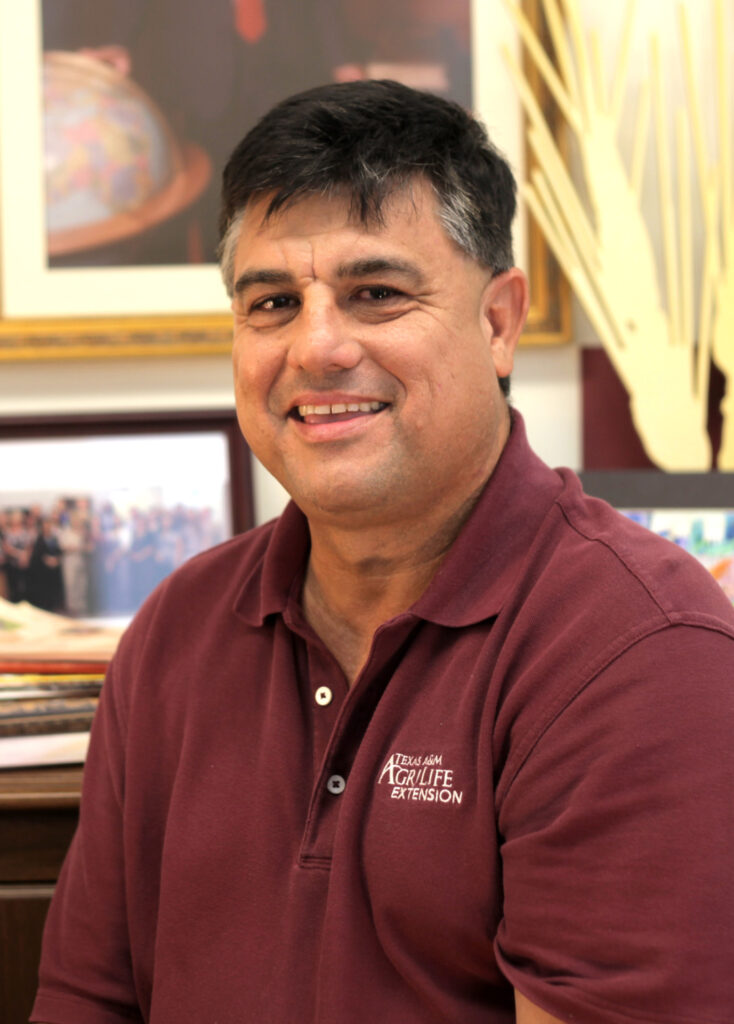 A smiling man, Juan Ancico, in a Texas A&M AgriLife Extension logoed shirt. He was named a Regents Fellow