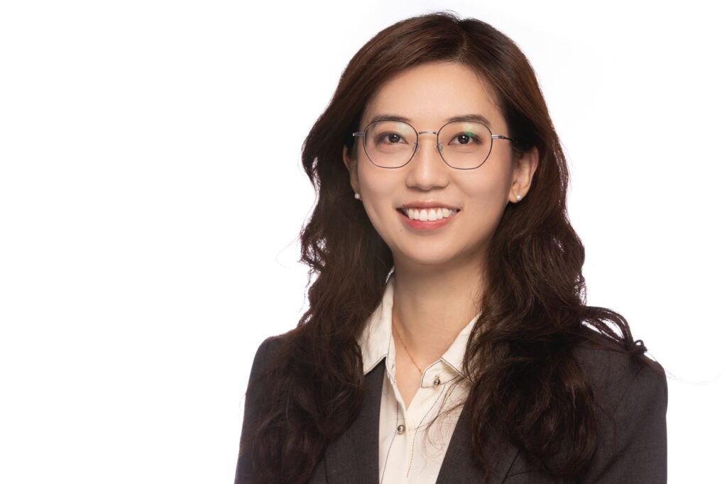 A head and shoulders photo of Dr. Li-Ching, who will be teaching environmental economics. She is wearing a black jacket, white shorts, and glasses. 