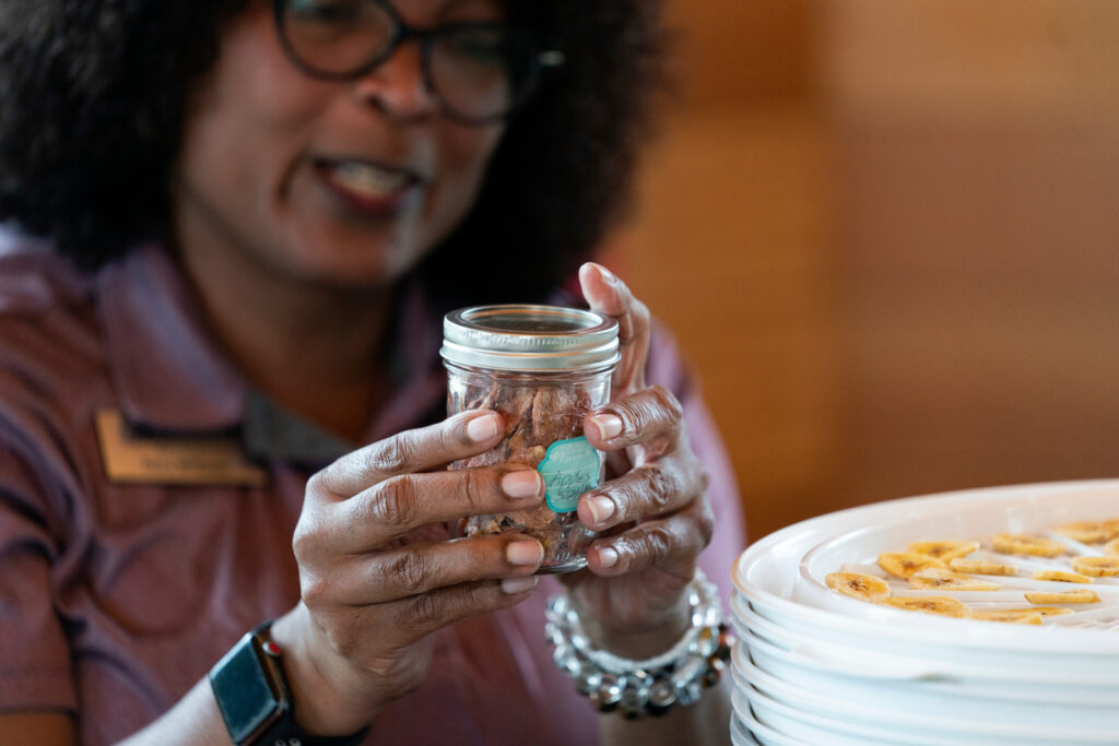 A woman attaches a label to a small mason jar 