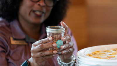 A woman attaches a lable to a small mason jar like homemade gidt would be made,