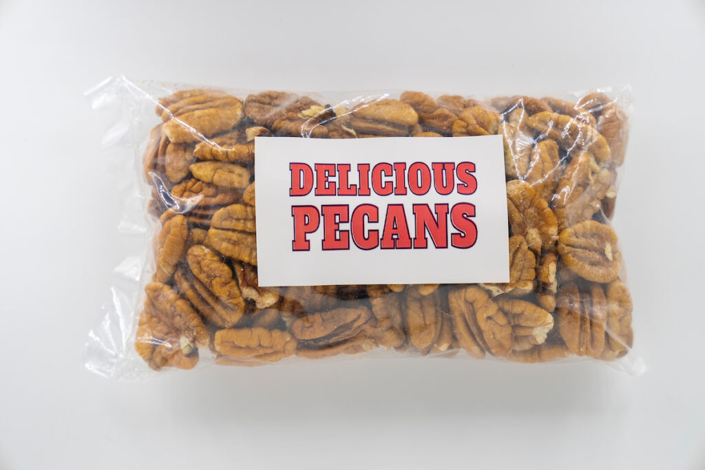 A clear bag of pecans that looks like a homemade gift with a label that reads Delicious Pecans