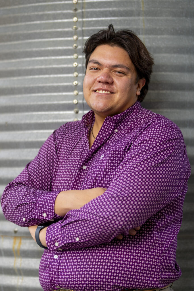 Dylan Sione leans against a grain silo with his arms crossed. He is wearing a purple shirt. Sione's involvement on campus helped him pursue Texas A&M's "other" education. 