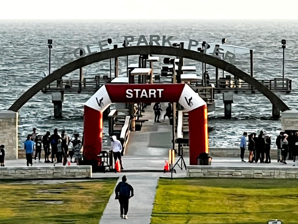 A blow up arch with Start on it is in front of a body of water. There are people standing on each side of it and there is a person walking toward it. The photo is from the Keeping Diabetes at Bay 5K Walk/Run.