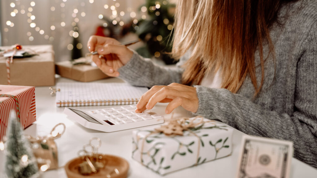 Woman sitting at a table while working on her budget, estimating money for Christmas expenses and gifts.