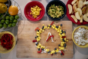 Bowls of fruit surround a cutting board with an AgriLife logo made from chopped fruit.