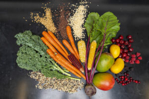 A spread of fruits, vegetables and grains on a black countertop. All are part of healthy eating. 