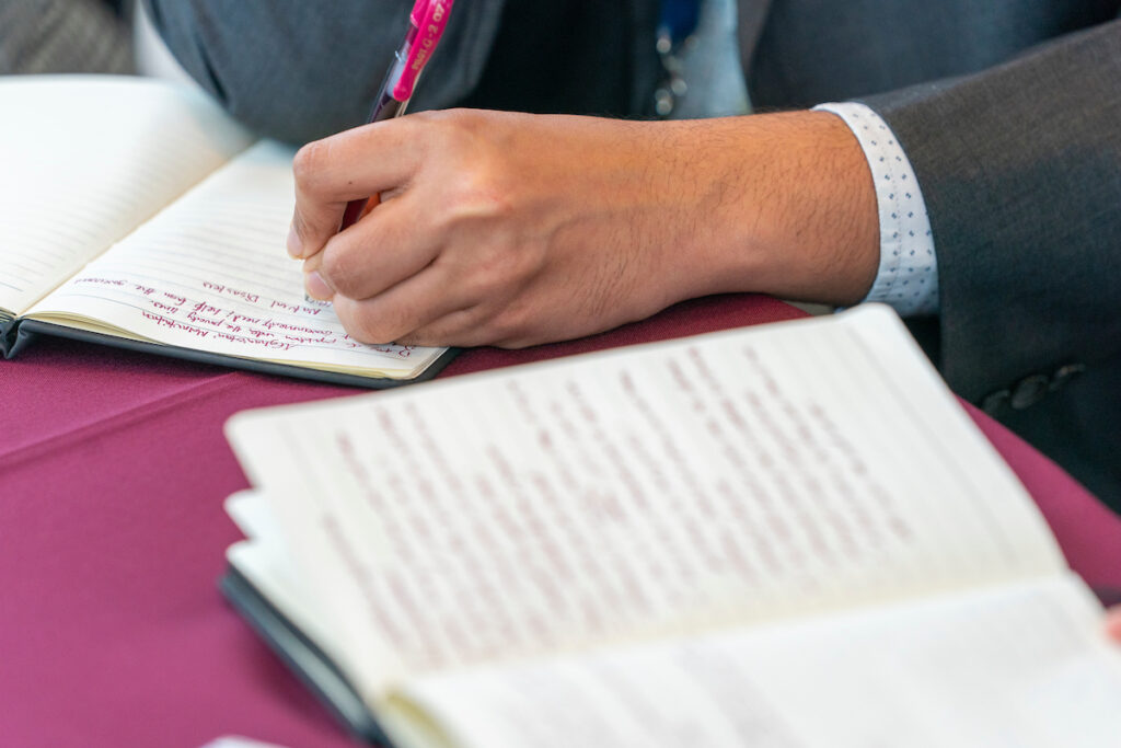 A hand is writing notes in a notebook. The Feb. 7 OneOp webinar will help people navigate through the complexities of Social Security disability benefits. 