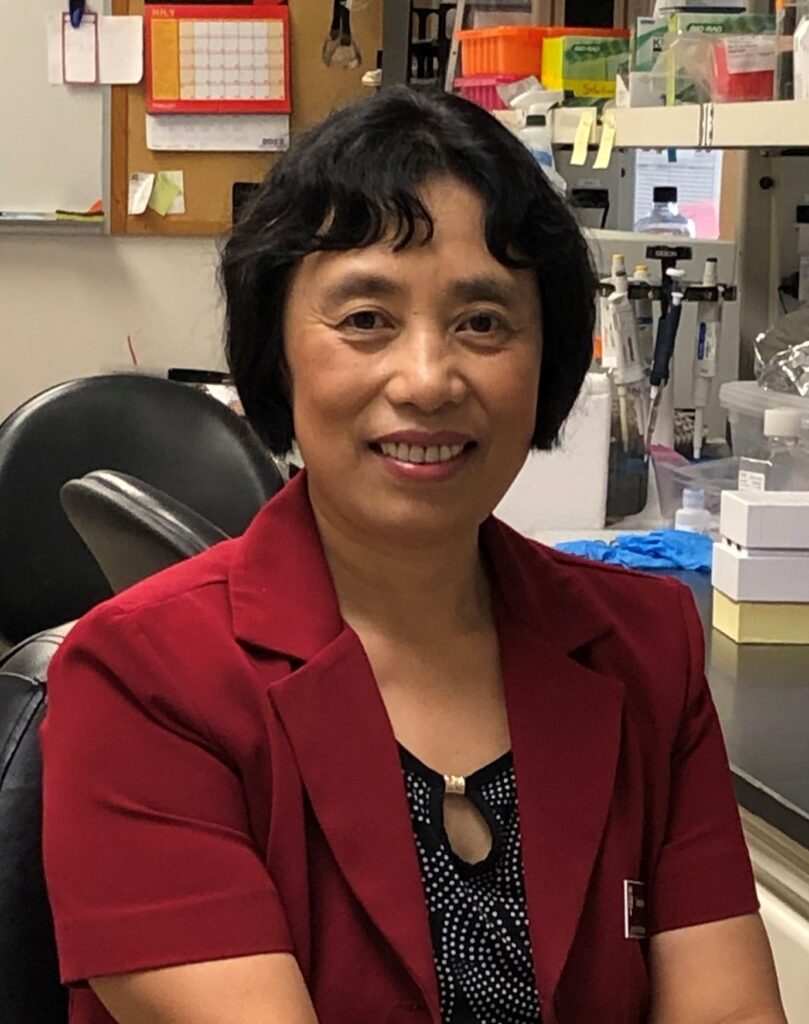 Yuxiang Sun, Ph.D. sitting in her lab, wearing red coat