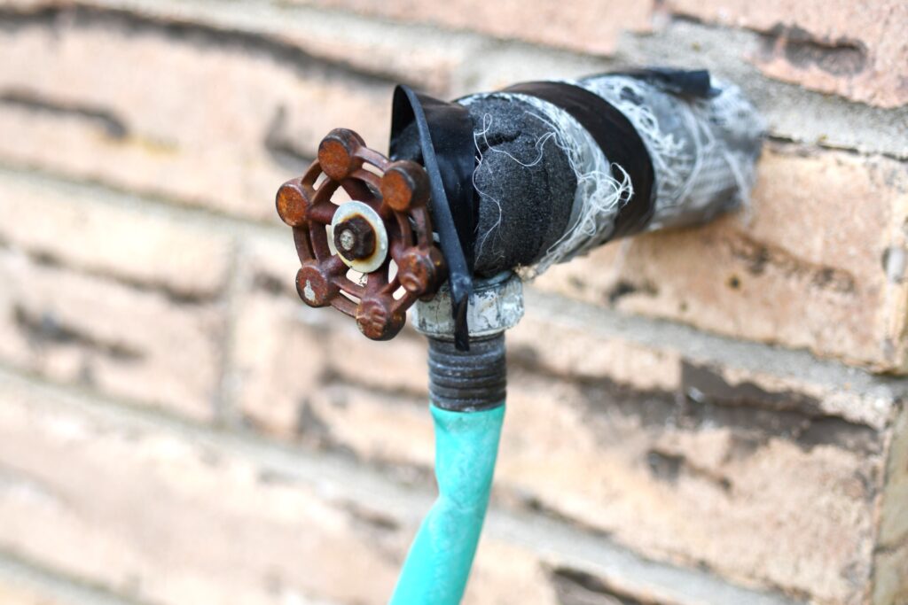 A water spigot with a hose attached. 