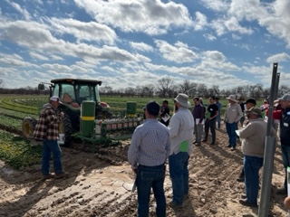 A group of people gather for a field day led by Larry Stein to learn about best practices in agriculture. 