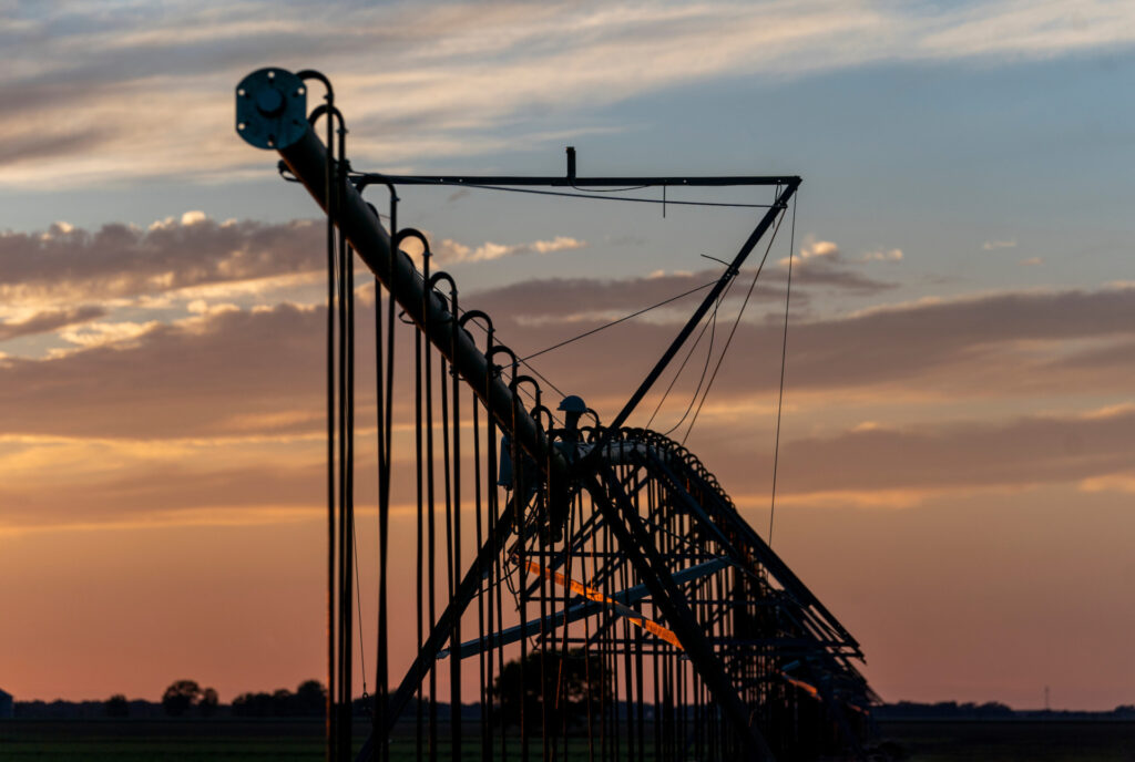 The silhouette of an irrigation pivot with sunset in the background. 