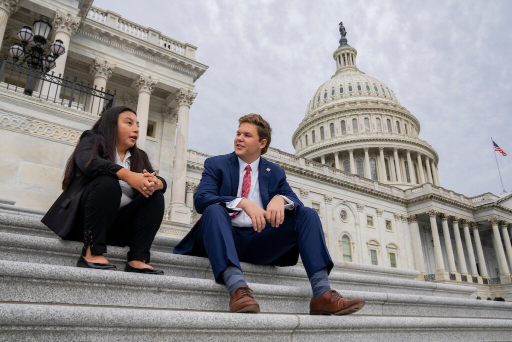 A man and a woman sit on the steps of the capitol in Washington, D.C.