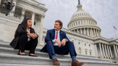 A man and a woman sit on the steps of the capitol in Washington, D.C.