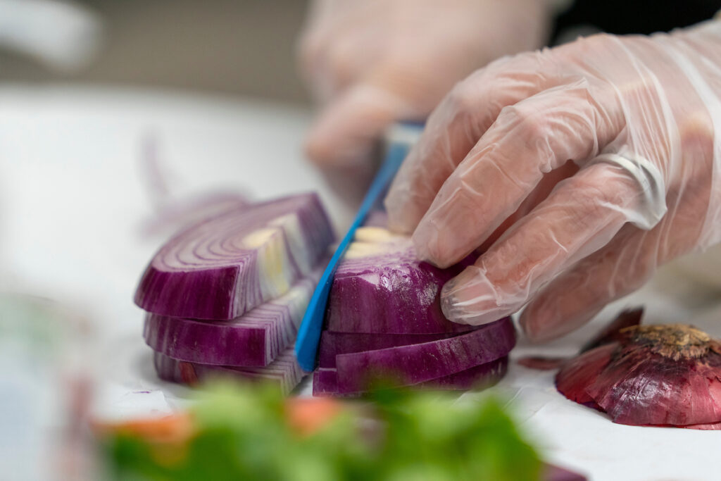 A person's hands are cutting a purple onion to add to a dish. An Instant Pot cooking class in Waco on March 12 will introduce participants to the popular electric pressure cooker and provide tips and recipes that they can try at home. 