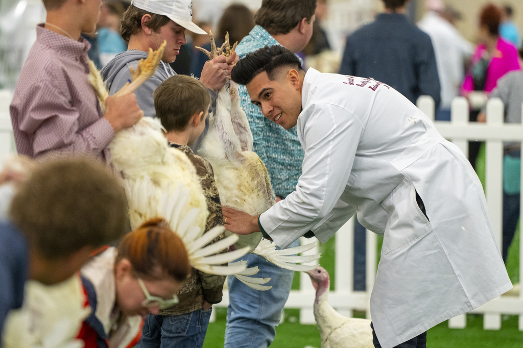 Daniel De Leon speaking to a small boy while examining a chicken