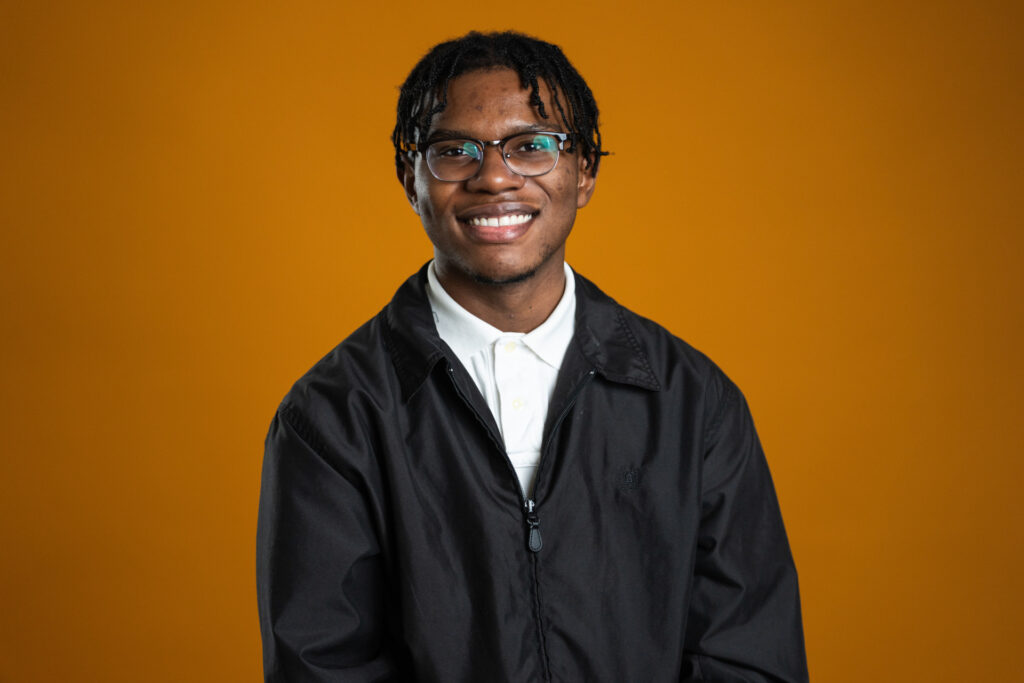 Headshot of entomology major Kwency Ashley. He is wearing a white shirt with a dark jacket. He is also wearing glasses. 