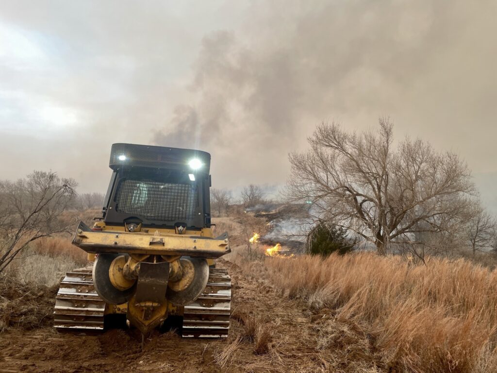 A dozer being used in a field to help contain the Smokehouse Creek Fire, which has become the largest wildfire in Texas history