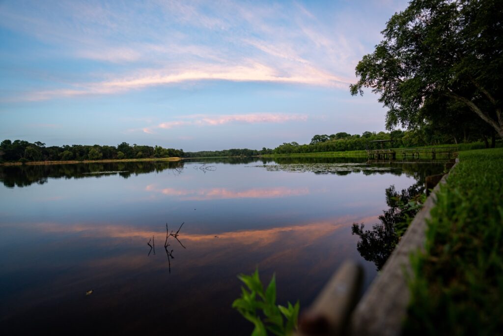 A shoreline with clouds reflecting off a body of water. A Texas Watershed Steward meeting on Feb. 28 will discuss water quality in the Highland Bayou watershed.