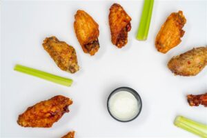 A half circle of chicken wings with celery and dressing in the middle. 