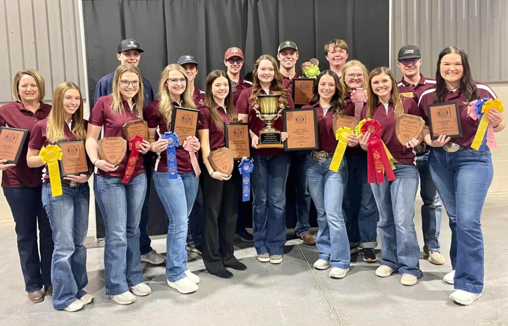 A meat judging team photo with Kadie Graves and lots of students holding ribbons of different colors as well as plaques