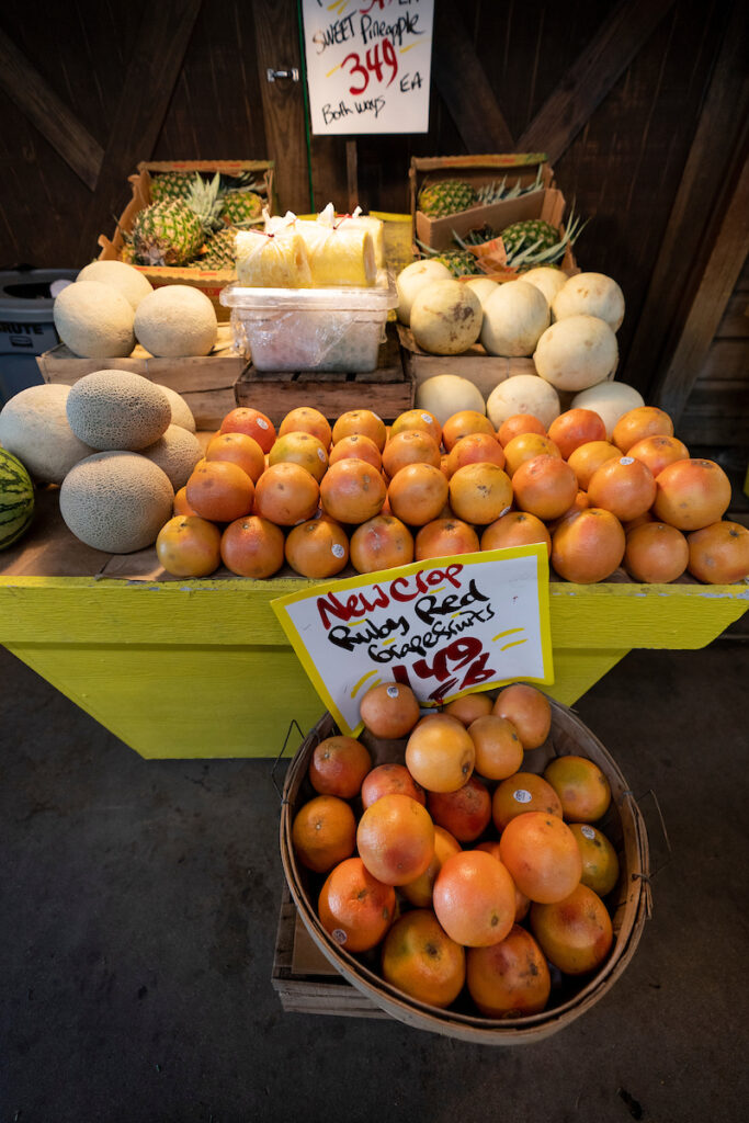 An arrangement of whole fruit for sale, including cantaloupes, pineapples and grapefruit. 