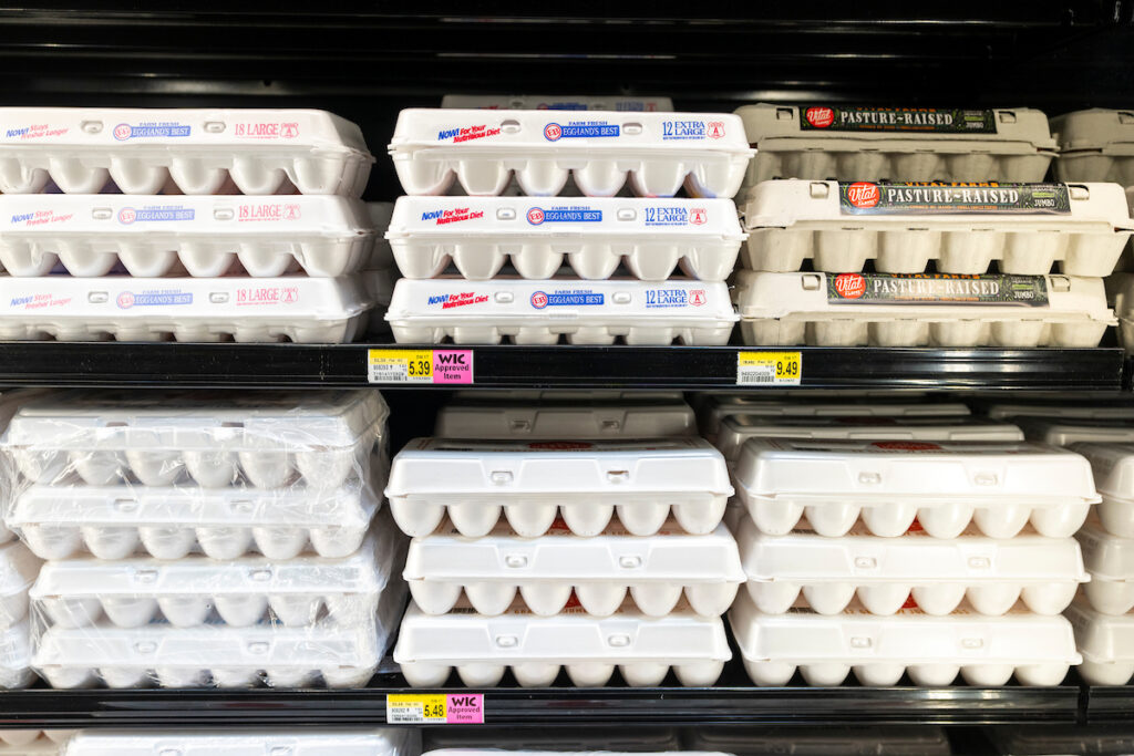 Full egg cartons sitting in a grocery store refrigerator. 